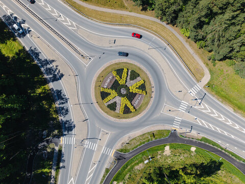 Aerial view of a roundabout with decorative landscaping and the name Ulbroka in the center, surrounded by roads and forest, Ulbroka, Ropazi Municipality, Latvia.