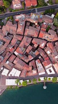 Aerial view of Garda town with tiled rooftops, narrow streets and waterfront promenade surrounded by cypress trees