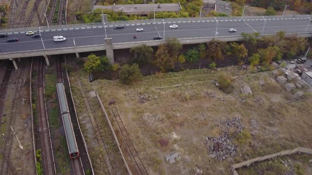 Aerial view of a train moving on the tracks in Yerevan, Armenia. The drone footage captures the railway system, surrounding buildings, and the urban landscape from a height.

