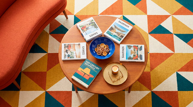 Overhead view of midcentury coffee table with design books on colorful rug