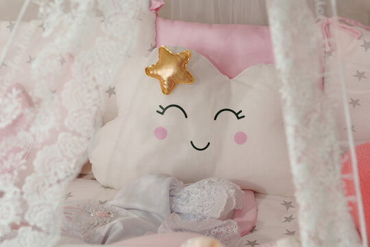 Cute white cloud-shaped pillow with a smiling face inside baby crib.