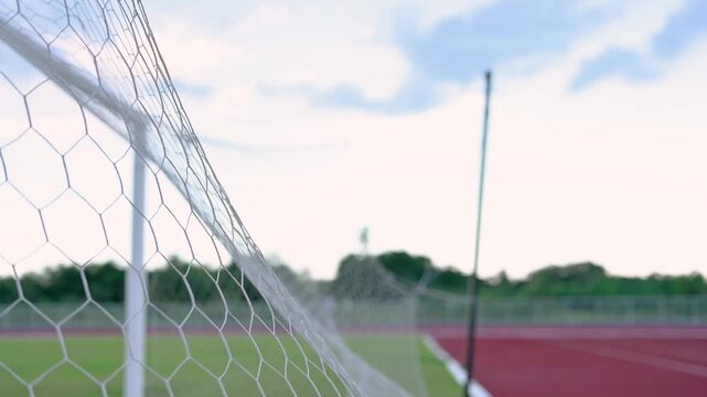 Breaking the Limits Concept: Powerful Shot of Soccer Ball Striking the Inside Net Under Bright Daylight