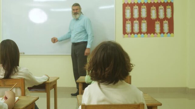 Multi-ethnic elementary school children assembling DIY robotic models during a STEM class with a senior teacher.
