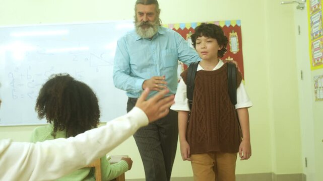 Multi-ethnic elementary school children assembling DIY robotic models during a STEM class with a senior teacher.