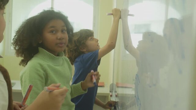 Multi-ethnic elementary school children assembling DIY robotic models during a STEM class with a senior teacher.