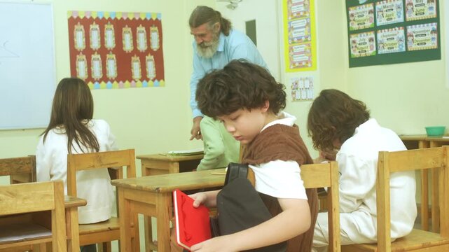 Multi-ethnic elementary school children assembling DIY robotic models during a STEM class with a senior teacher.