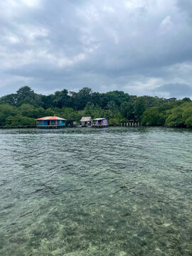 Stilt house and lush mangroves in Bocas del Toro bay, Panama. Calm rippling water and soft natural light, cloudy sky