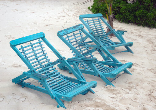 Three blue wooden beach chairs on tropical sand