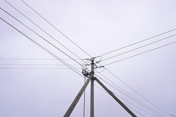 Fototapeta premium Power lines and telephone pole against grey sky. Electrical infrastructure, utility poles. Urban scene, telecommunications, energy distribution, minimalist composition.