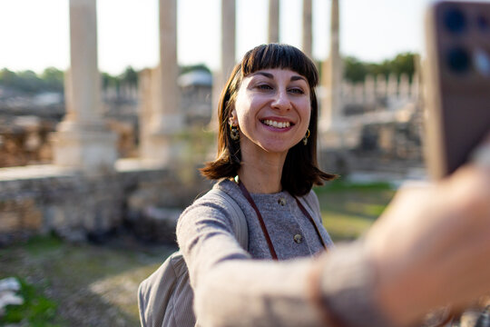 A girl is filming content. A stylish tourist strolls among ruins with a backpack, photographing landmarks for her blog and social media. Israel. Beit She'an.