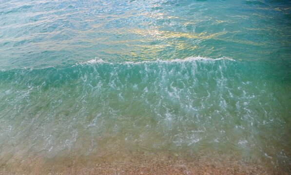 Turquoise sea surface with waves splash on the shore, ariel water splash background