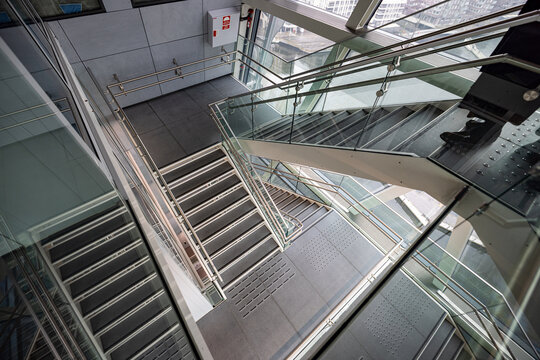 Modern glass staircase curves downward in a sleek interior