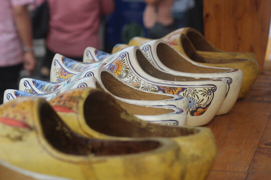 Close-up of traditional hand-painted Dutch wooden clogs lined up on a wooden table