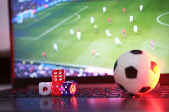 Online soccer gambling and betting. Balls and dice in front of a laptop with live soccer broadcasts. Live scores and results.
