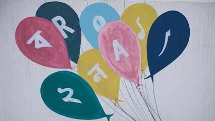 Colorful balloon mural with letters painted on a white exterior wall © MDJAHIDHASAN
