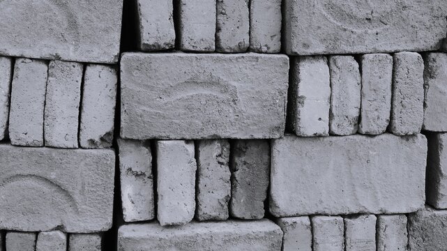 Black and white stacked concrete block wall with rough bricks, uneven gaps, dusty marks, and raw construction texture.