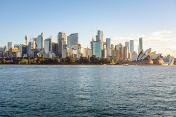 Naklejka premium Sydney, Australia - May 01, 2026: Central Business District skyline and Opera House under clear sky at sunset in autumn.