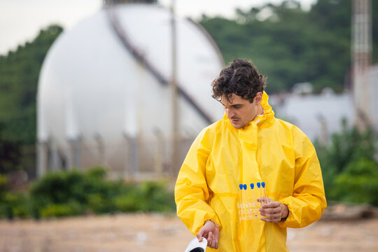 Environmental scientist in hazmat suit collecting samples, Professional researcher holding test tubes near industrial facility, Hazardous materials expert monitoring pollution levels at chemical plant