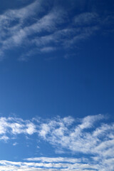 Obraz premium A clear blue sky with scattered white clouds forming light patterns. A sky background for nature or abstract themes.