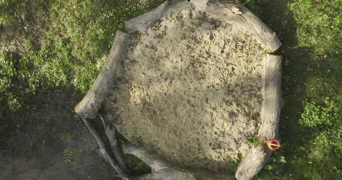 Senkrechte Drohnenaufnahme eines Sandspielplatzes mit heller Sandfl&auml;che und nat&uuml;rlichen Strukturen, aufgenommen aus der Vogelperspektive in ruhiger Outdoor-Umgebung