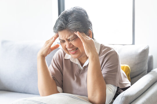 Sick, stress caucasians senior. Mature, adult elderly woman having migraine pain, headache symptom, feeling unhealthy, suffering from dizzy when sitting on sofa. Health care problems of older people.