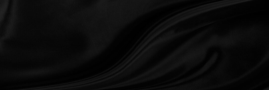 Black gray satin dark fabric texture luxurious shiny that is abstract silk cloth panorama background with patterns soft waves blur beautiful.
