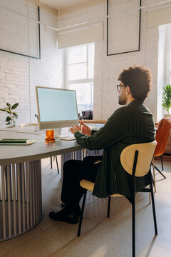 A man uses a computer with a white screen 