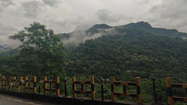 Monsoon mist and low clouds drifting over the mountain valley highway near Kathgodam, Uttarakhand, India.