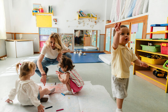 Teacher interacting with children during creative drawing activity