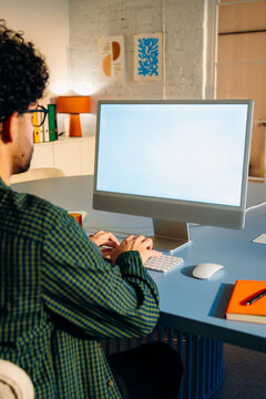 A man uses a computer with a white screen 