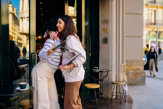 Two women hug each other standing on a city street