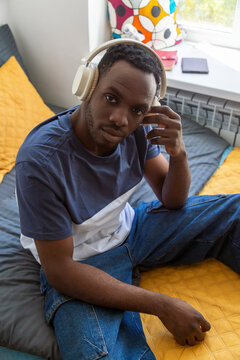 Student listening to music with headphones in dormitory bedroom