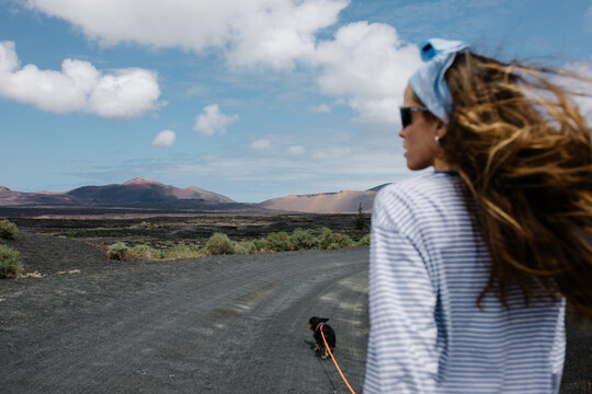 Woman walking her dog on a dirt road in Lanzarote's volcanic landscape