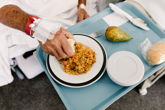 Patient with an IV catheter in their hand squeezes lemon over rice