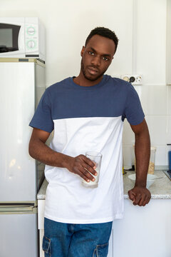Young man holding glass of water in shared kitchen