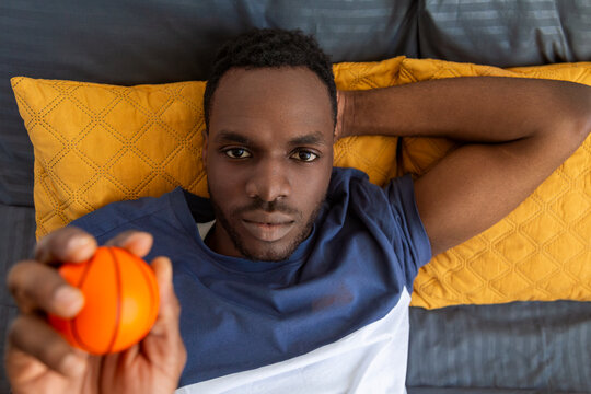 Man holding small pumpkin lying on bed with yellow pillows