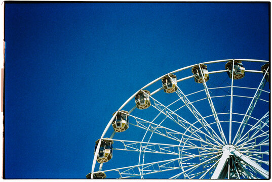 cropped view of a ferris wheel against the blue sky, 35mm film