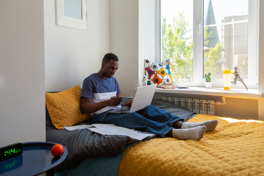 Student using laptop on bed in dormitory room