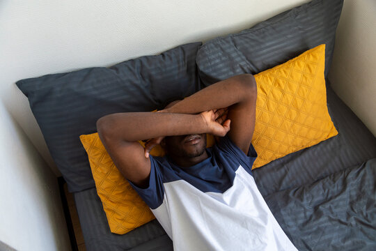 Man stretching in bed after waking up in dormitory room