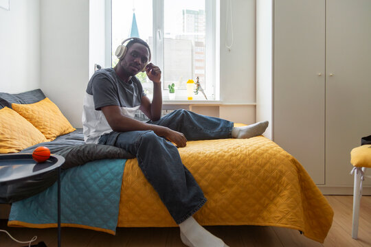 Student listening to music on bed in dormitory room