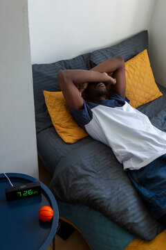 Student resting on bed in dormitory room