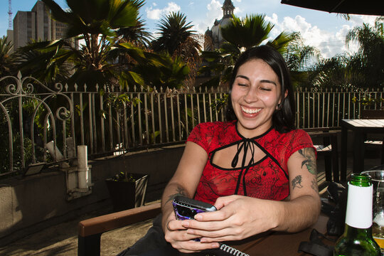 Woman Laughing While Looking at Smartphone in Medell&iacute;n at Sunset