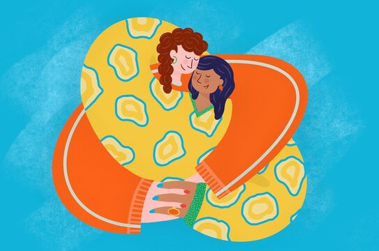 Women hugging in brightly coloured clothes.