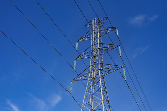 Large high-voltage pylons and transmission lines supply electricity to the capital city under a clear blue sky. This image showcases the infrastructure, reflecting the concept of urban growth.