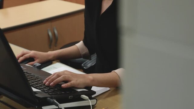 실내 사무실 책상에서 노트북 키보드와 마우스를 활용해 업무 작업에 집중하고 있는 인물의 상체와 손동작을 포착한 전경 동영상 클립입니다.