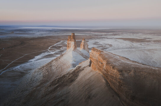 Aerial view of the dramatic limestone rock formations of Bozhira, with vast desert plains and winding tracks in Karakiya District, Mangystau Region, Kazakhstan.