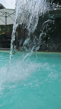 Water falls into pool creating splash and ripples on surface