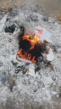 Fire burns brightly among scattered trash and broken pieces on the ground