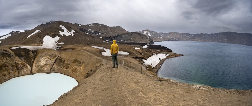 Tourist at the crater rim, crater lake V&iacute;ti and &Ouml;skjuvatn in the crater of Askja volcano, volcanic landscape, mountain massif Dyngjufj&ouml;ll, Icelandic highlands, Vatnaj&ouml;kull National Park, Iceland