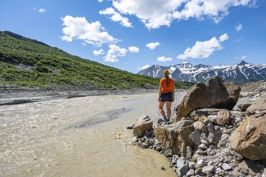 Tourist enjoying views of Miller Creek meltwater river at Castner Glacier, Delta Range, Alaska Range, Richardson Highway, Alaska, USA